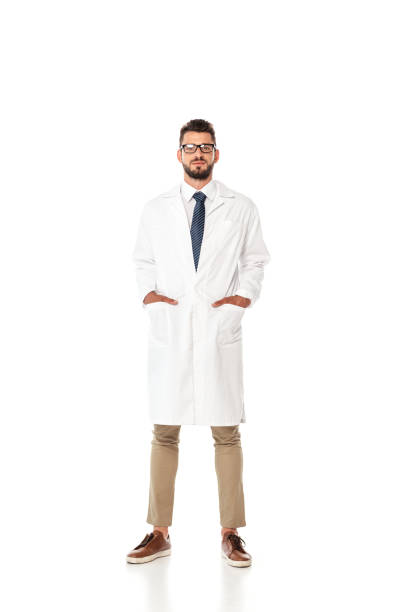 istock Handsome doctor with hands in pockets of white coat looking at camera on white background 1257596268