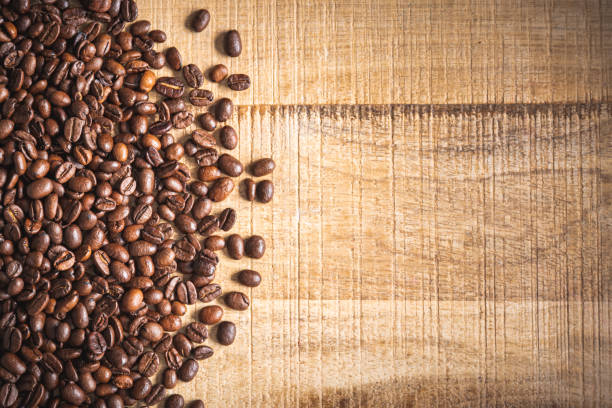 Roasted brown coffee beans spilled on wooden table background.