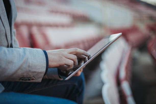 Young man using digital tablet on the empty football stadium
