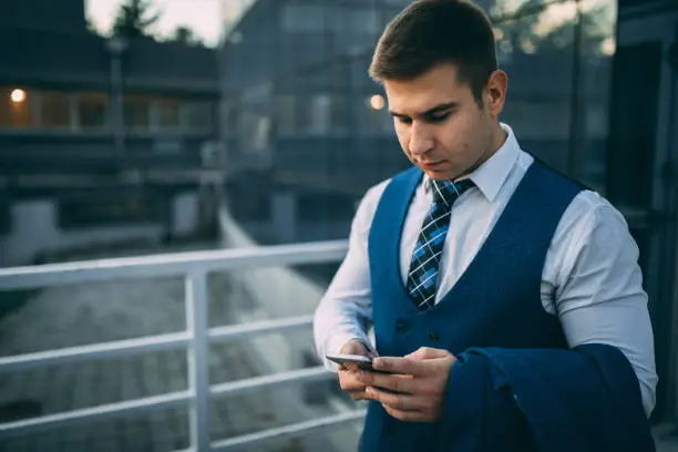 Photo of Businessman using smartphone in front of the office building