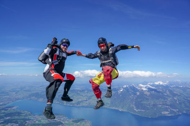 freifallflieger steigen durch luftigen himmel über berglandschaft - clothing anticipation central europe switzerland stock-fotos und bilder