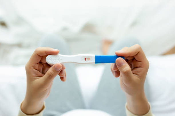 femme enceinte heureuse retenant le test de grossesse, examinent le test positif, jeune femme a le bébé ou le foetus dans le ventre. jeune mère attendant le nouveau-né prénatal, grossesse, maternité, concept d’attente - medical test people women beauty photos et images de collection