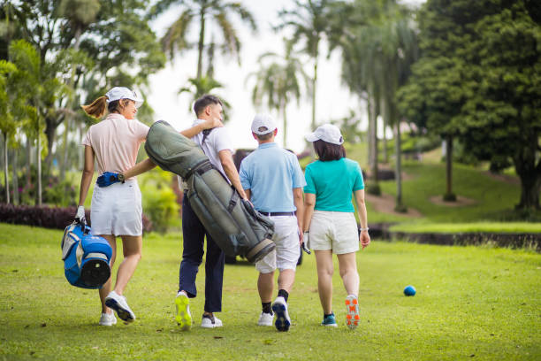 アジアの中国人の家族は、彼らの週末の活動のためにゴルフコースで笑顔と楽しんでいます.彼らはゴルフカートに向かって歩いています。 - golf cart golf bag horizontal outdoors ストックフォトと画像