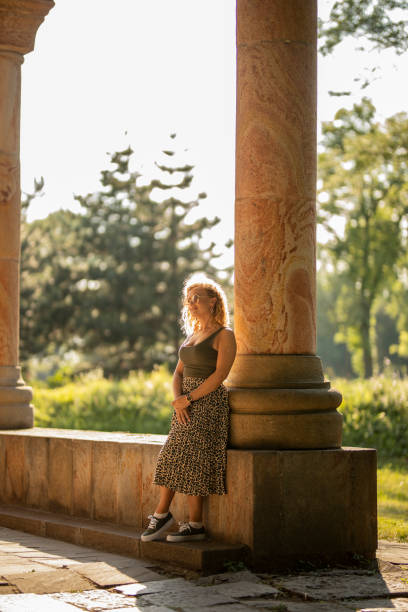 istock Young woman standing in park on sunny day 1257602455