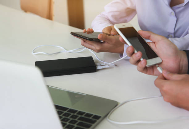 istock Two people connecting the mobile to a power bank. Technology device charge sharing concept. 1257605860