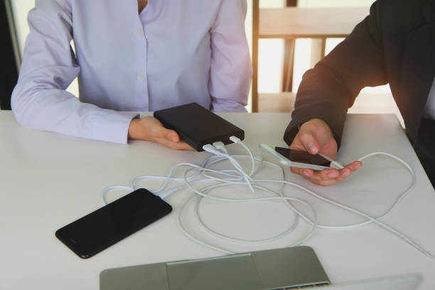 istock Two people using two mobile phone sharing USB Power Bank on a table to charge the mobile devices. Technology device charge sharing concept. 1257605931