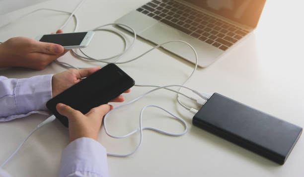 istock Two people using two mobile phone sharing USB Power Bank on a table to charge the mobile devices. Technology device charge sharing concept. 1257605945