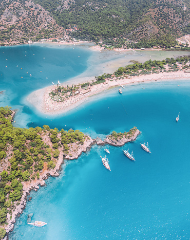 Beautiful aerial landscape view of Sandy Blue Lagoon beach coastline and turquoise colour Mediteranean Sea's azure water and green forest in Ölüdeniz, Türkiye. Summer vacation concept.
