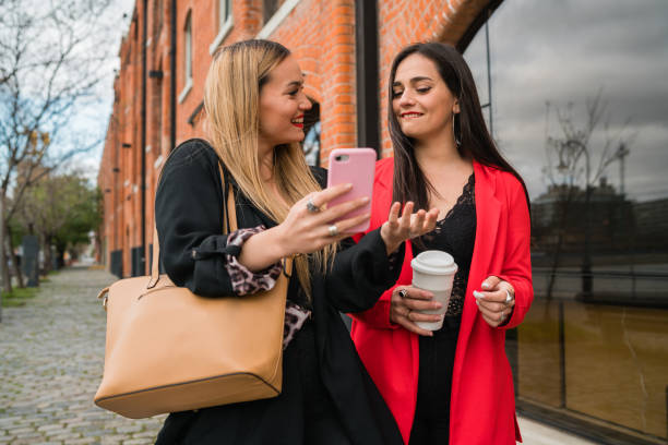 istock Two young friends using their mobile phone outdoors. 1257611608