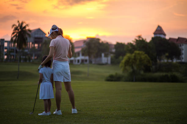 pewne chińskie dzieci z matką ciesząc się cudowny czas zachodu słońca podczas sesji na polu golfowym. - standing family golf loving zdjęcia i obrazy z banku zdjęć