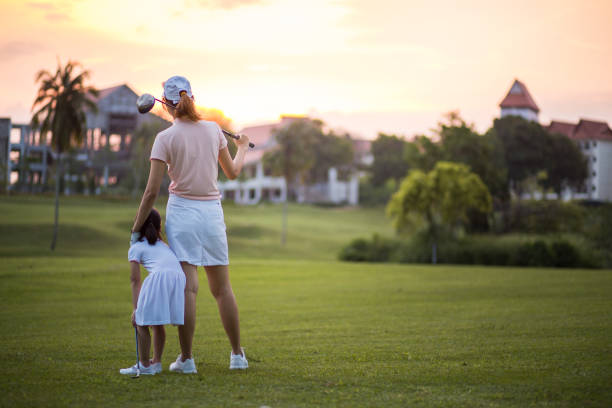 pewne chińskie dzieci z matką ciesząc się cudowny czas zachodu słońca podczas sesji na polu golfowym. - standing family golf loving zdjęcia i obrazy z banku zdjęć