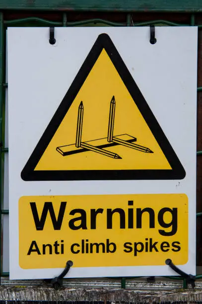 Warning sign with yellow triangle notice of anti climb spikes