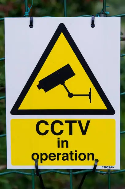 Warning sign with yellow triangle notice of CCTV in operation