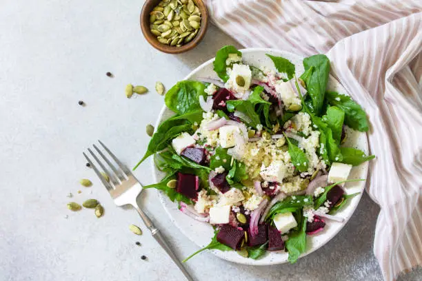 Healthy salad with couscous, soft cheese, beetroot and vinaigrette dressing. Top view flat lay background.