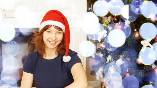 christmas beauty woman. Happy new year. Fir tree. Surprise present. Girl in red santa cap. Winter bokeh ligth concept. Home interior. Copyspace. Horizontal