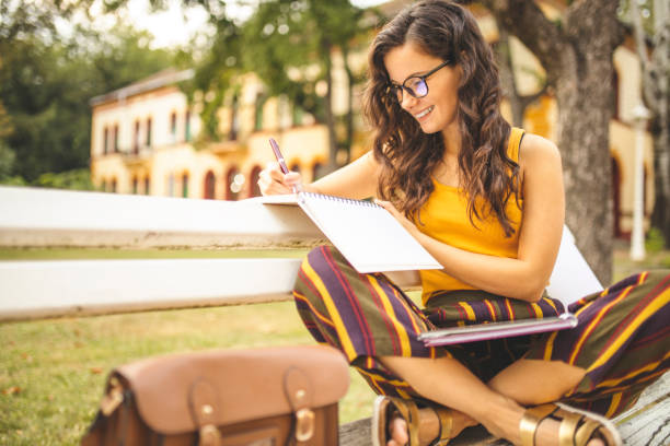 istock Female student learning and sitting on park bench 1257623110