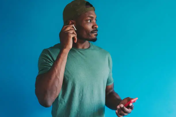 African American man is double-tapping in-ear headphones to answer a call