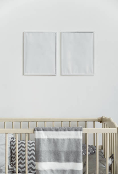 istock Two white empty wall frames above infant baby cot bed with gray blanket 1257625750