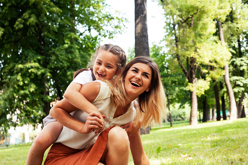 young pretty mother walking with little cute daughter outside in green park, lifestyle poeple concept closeup