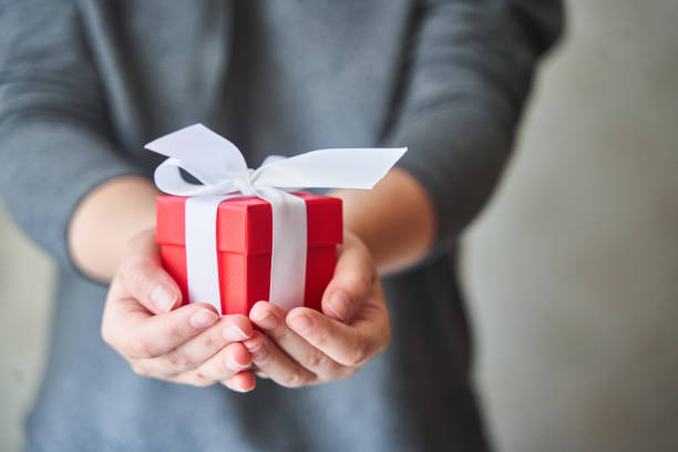 istock Woman holding small red present box in hands 1257625917