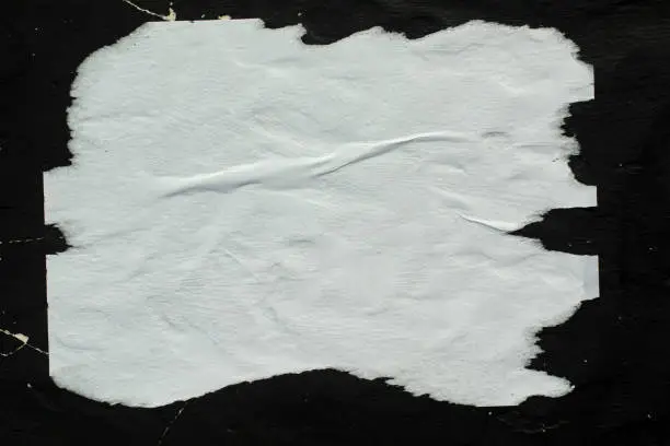 Photo of White crumpled paper pasted on a black wall.