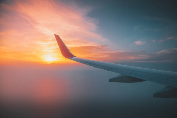 Seeing the sunset on flight Sunset under aircraft wing skyline view from airplane in flight. stratosphere airplane cloudscape mountain stock pictures, royalty-free photos & images