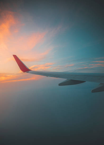 Seeing the sunset on flight Sunset under aircraft wing skyline view from airplane in flight. stratosphere airplane cloudscape mountain stock pictures, royalty-free photos & images