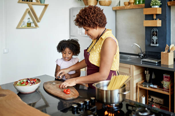 istock Mother Showing Young Daughter How to Slice Grape Tomatoes 1257647488