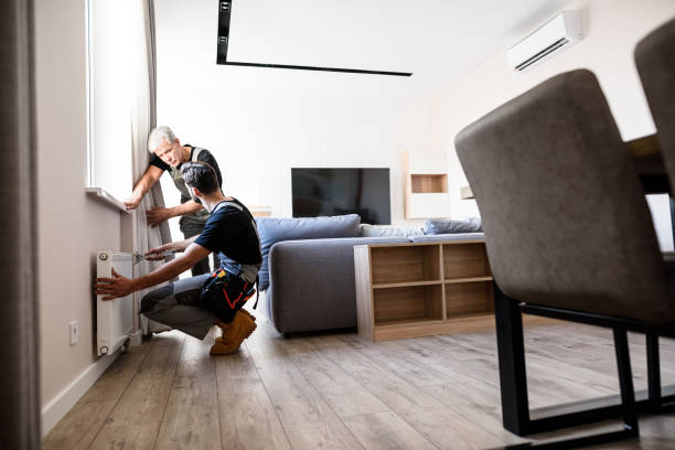 istock Full length shot of two professional plumbers, workers in uniform fixing or installing heating radiator. Construction, maintenance and repair concept. 1257648177