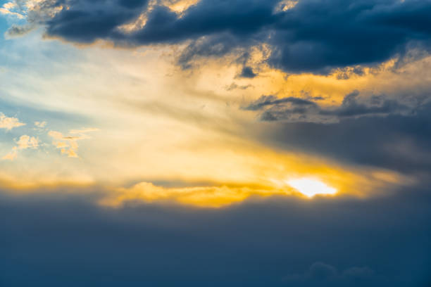 Skyscape cloudscape colorful yellow blue sky during evening sunset with sun behind clouds looking up in Santa Fe, New Mexico