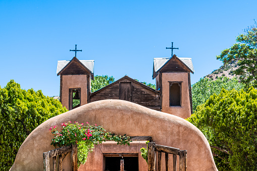 Famous historic El Santuario de Chimayo sanctuary church in the United States with entrance gate closeup of flowers in summer
