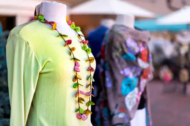 Outside store street in New Mexico city with blurry background and foreground closeup of green clothing dress shirt with colorful handmade necklace on mannequin