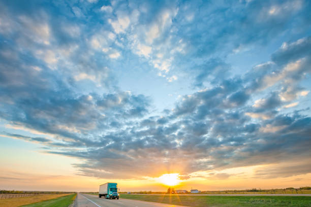 Truck passing under building storm clouds, infused with vibrant sunset hues, capturing the dynamic contrast of nature's elements in motion.