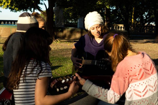 Senior homeless man playing music with a boy outdoors