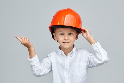 little boy in a construction helmet. the finger points in the direction of empty space. advertising concept for the construction