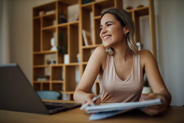 istock Portrait of a charming smiling university student, sitting at table with laptop and note pad and looking away. 1257664146