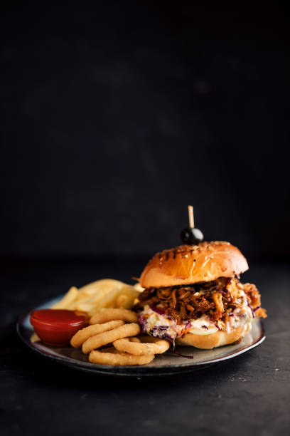istock Delicious burger and onion rings on dark background. 1257664283