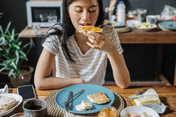 istock Asian Woman Eating Bread, Butter and Jam for Breakfast 1257664702