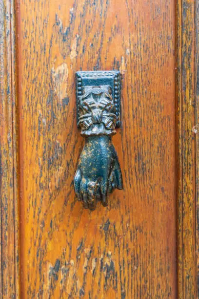 Europe, France, Dordogne, Hautefort. A metal door knocker in the shape of a hand in the town of Hautefort.