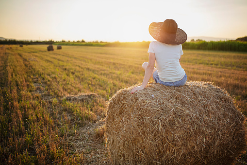 Woman sitting on a hay in a countryside