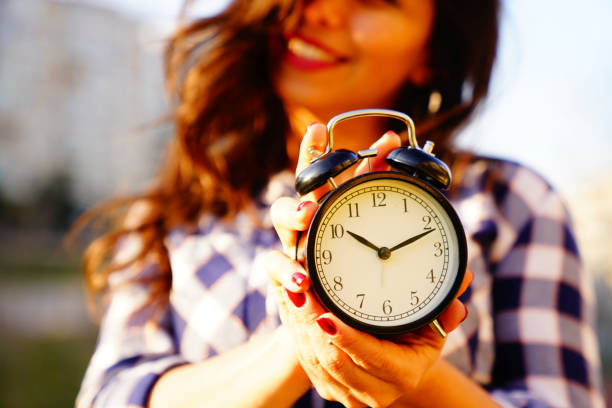 woman holding alarm clock in hands
