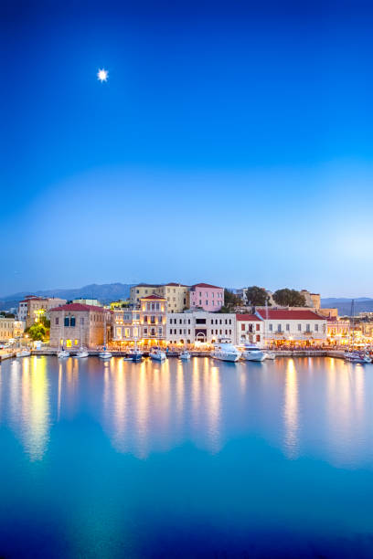 旅行の概念。クレタ島の青い時間に前景にフィシヒングボートとヨットのラインを持つハニアの旧ヴェネツィア港の絵のようなイメージ。垂直ショット - ハニア ストックフォトと画像