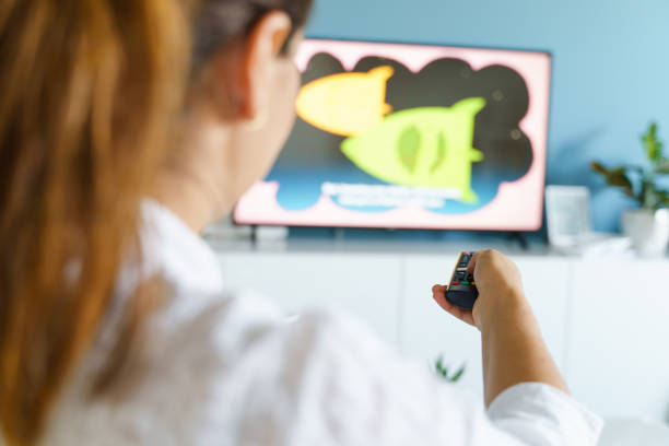 istock Back view on hand of unknown caucasian woman holding remote controller changing TV channel at home - Television or internet smart tv choosing content using modern technology leisure relaxation concept 1257672748