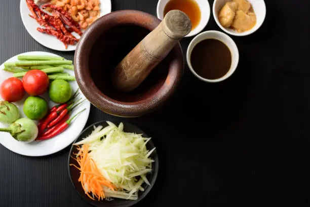 Thai cuisine, food ingredients and recipe for spicy papaya salad (Som Tum) on black background, Top view