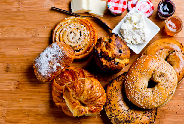 bagels, croissants, muffins, zimtbrötchen & donuts serviert mit frischkäse, butter, gelee & marmeladen. klassisches amerikanisches oder französisches frühstück oder brunch. verschiedenes frühstücksbrot & gebäck. - muffin cheese bakery breakfast stock-fotos und bilder