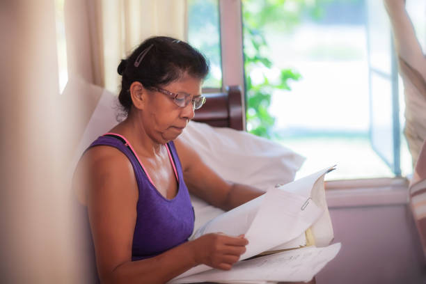 Latino woman comparing monthly mortgage statements, considering mortgage relief assistance or refinancing. stock photo