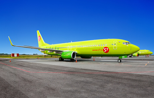 Novosibirsk, Russia - July 14, 2020: Tolmachevo Airport, airplane Boeing 737-800 on airfield blue sky background close up, s7 Airlines aircompany, passenger airliner, green jet plane stands on runway
