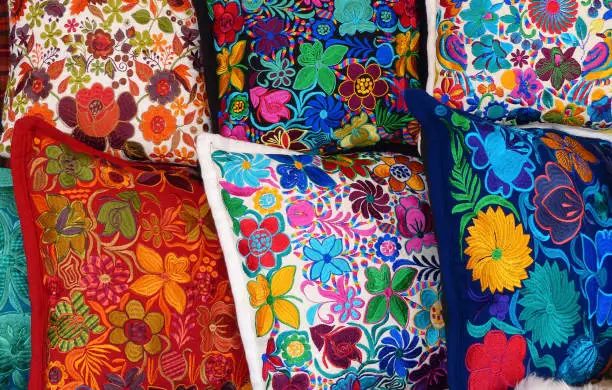 Close up of сolorful embroidered decorative textile pillows at the artisan's market in Otavalo, Ecuador. Otavalo city is famous for the skills of it's citizens in trade and monufacturing textiles and is one of the most famous markets and visited spots by tourists in South America and in Ecuador