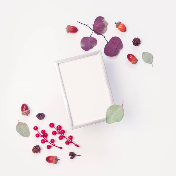 istock Autumn composition / template. The empty metal frame is on a white background. The layout is decorated with red berries, acorns, pine cones, dried leaves and plants. Flat lay. Top view. Copy space. 1257693815