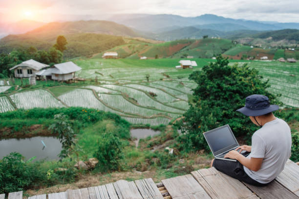 istock Male traveler blogger work remote on netbook computer while enjoying rice terrace nature landscape view outdoors. Young man using online banking for sending money everywhere you are from laptop 1257695746